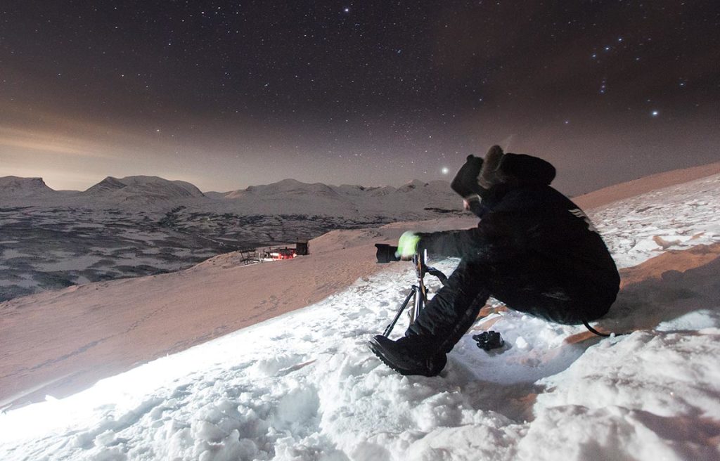 Fotógrafo trabalhando na neve fotografando a Aurora Boreal