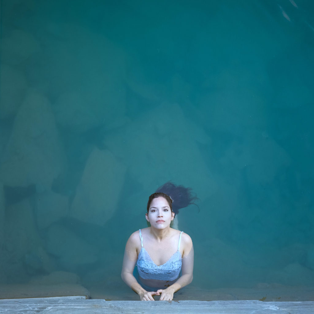 Retrato moça flutuando em água azul límpida