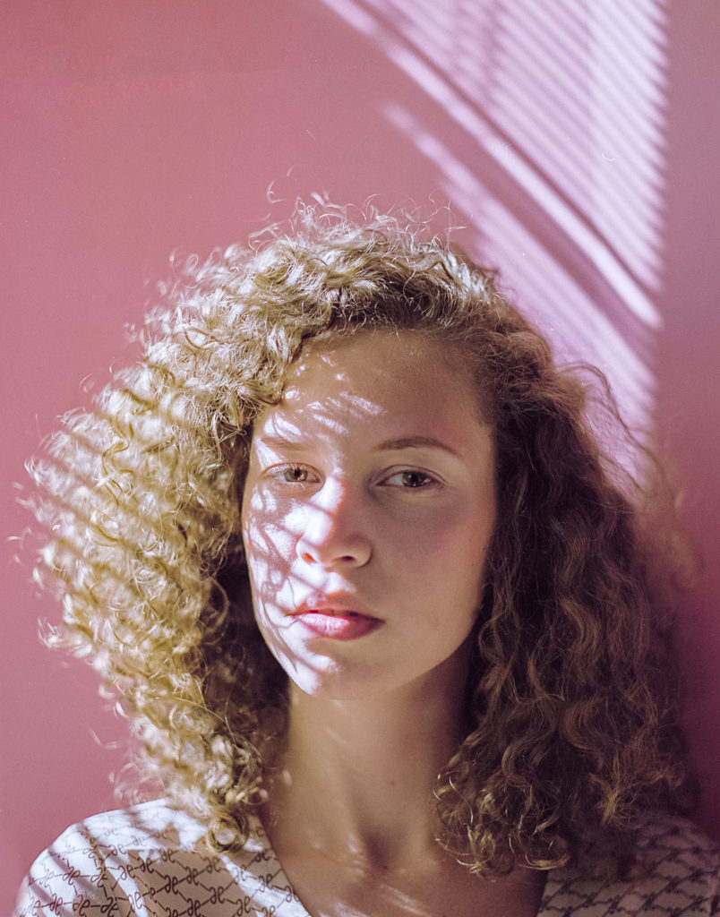 Retrato exemplo de fotografar com filme de modelo com fundo rosa e cabelos cacheados