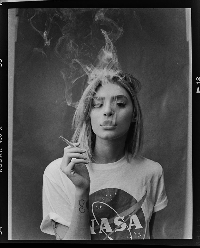 Fotografia com filme com bordas do negativo e modelo segurando cigarro